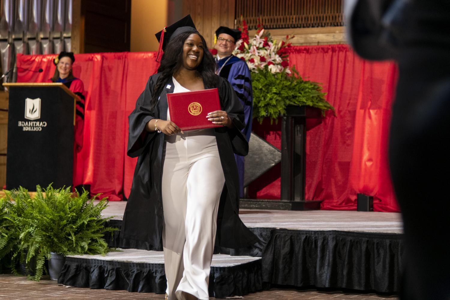 A 2023 <a href='http://zd6y.peakuniverse.com'>BETVLCTOR伟德登录</a> graduate beams as she leaves the Commencement stage after receiving her diploma from Carthage President John 吞下.